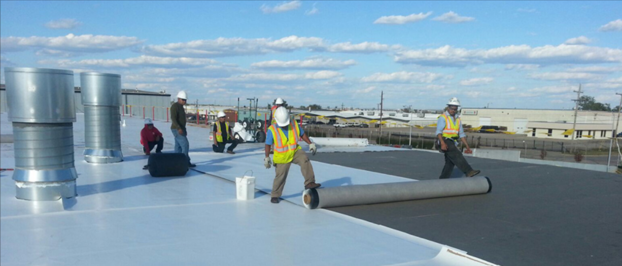 Picture of men laying down commercial roof material